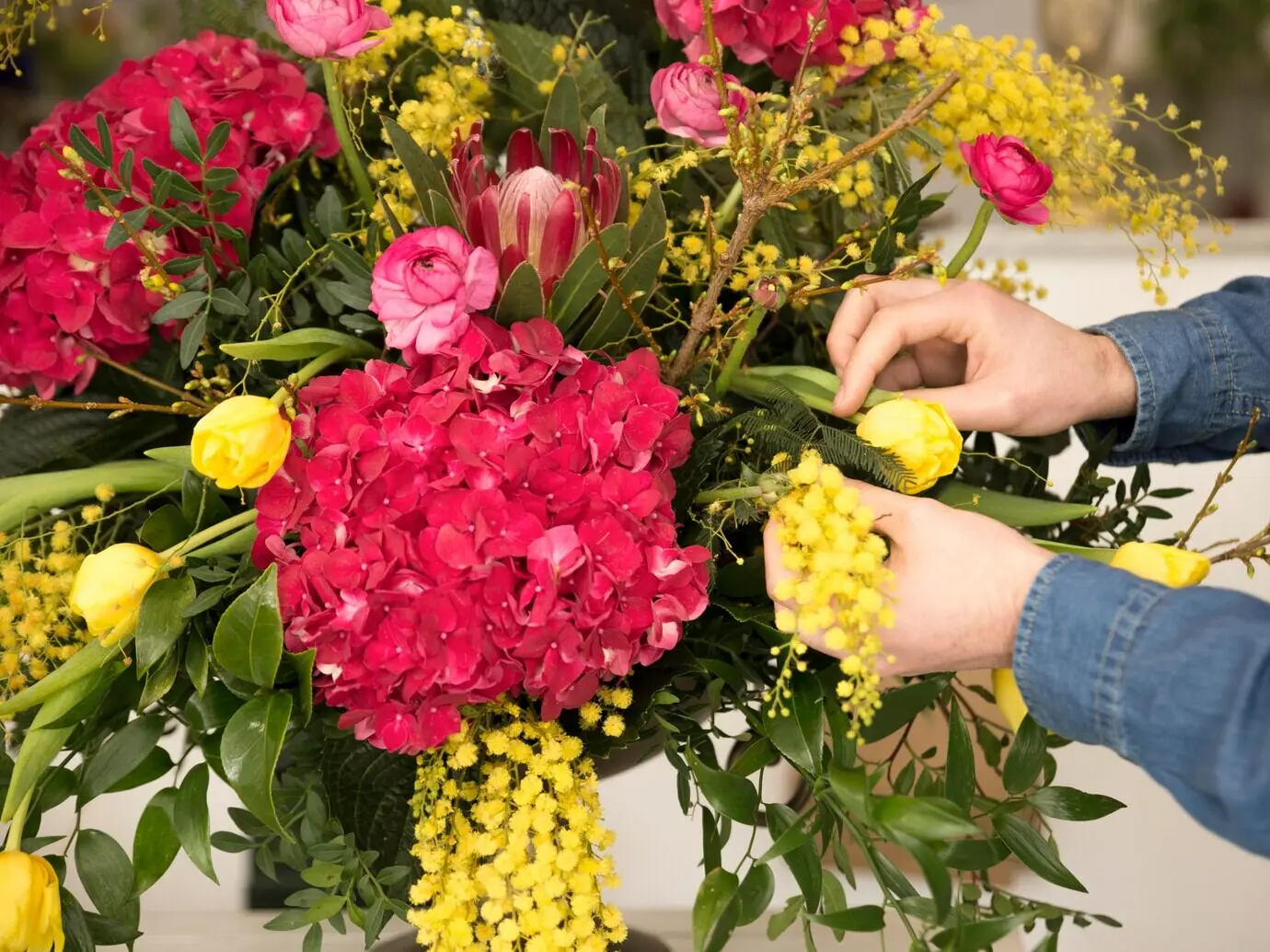 Nahaufnahme der Hand eines männlichen Floristen beim Arrangieren der Blumen in der Vase.