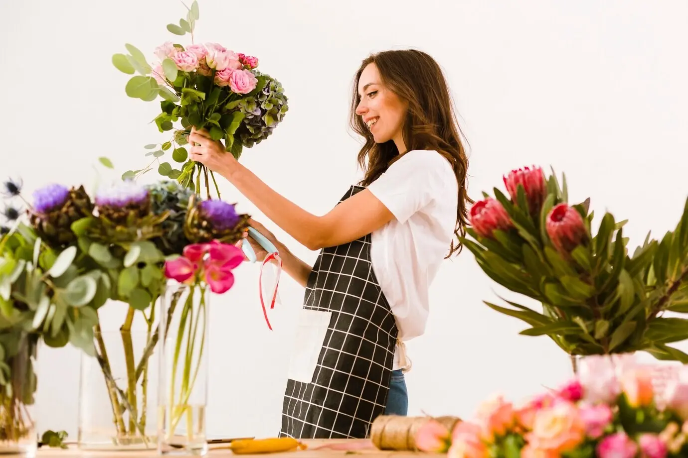 Halbnahe Aufnahme eines lächelnden Floristen, der einen Blumenstrauß bindet.